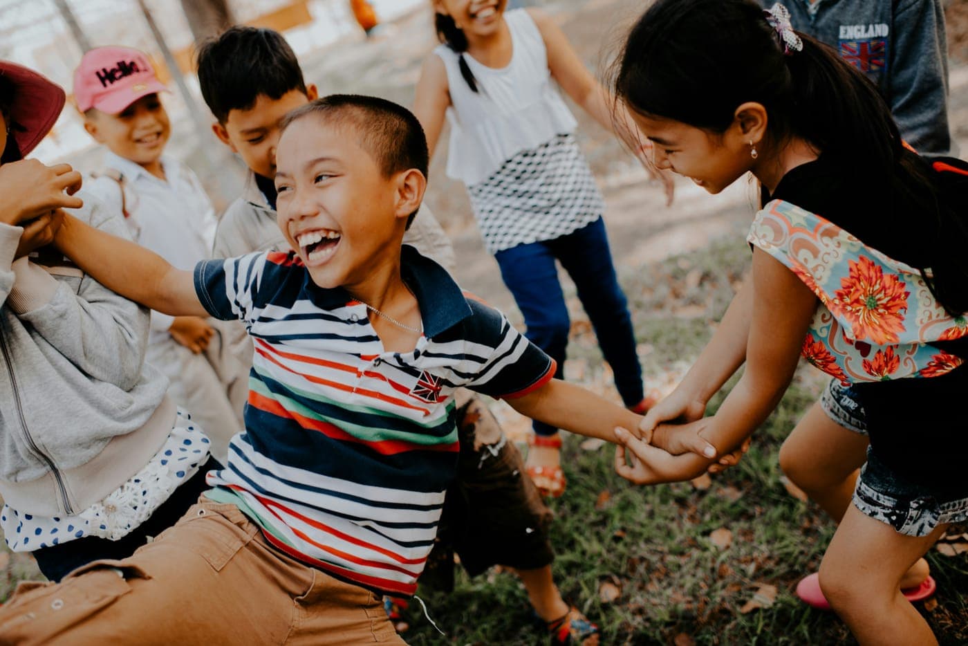Children laughing and holding hands while playing together outdoors